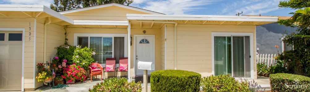 A small house with a porch, featuring a white front door and a mailbox.