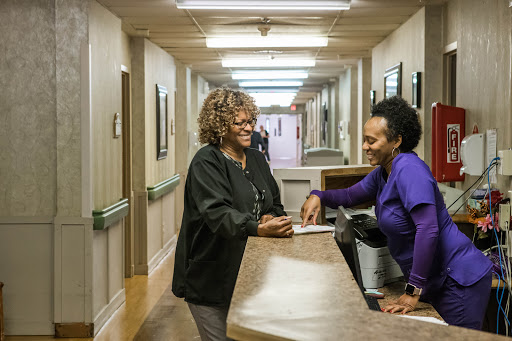 Two women engaging in a friendly conversation at a hospital reception.