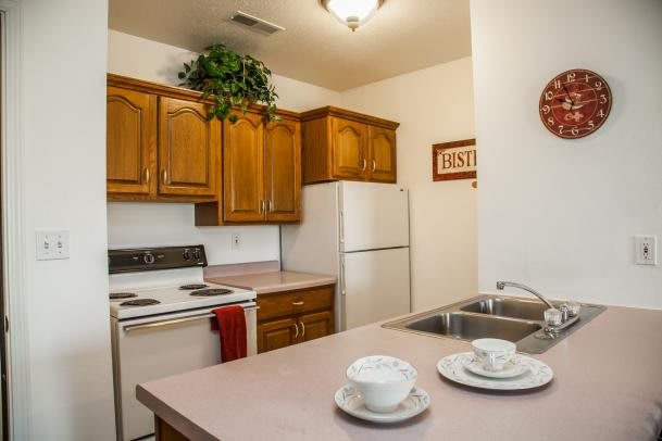 A cozy kitchen with wooden cabinets, a stove, and a refrigerator.