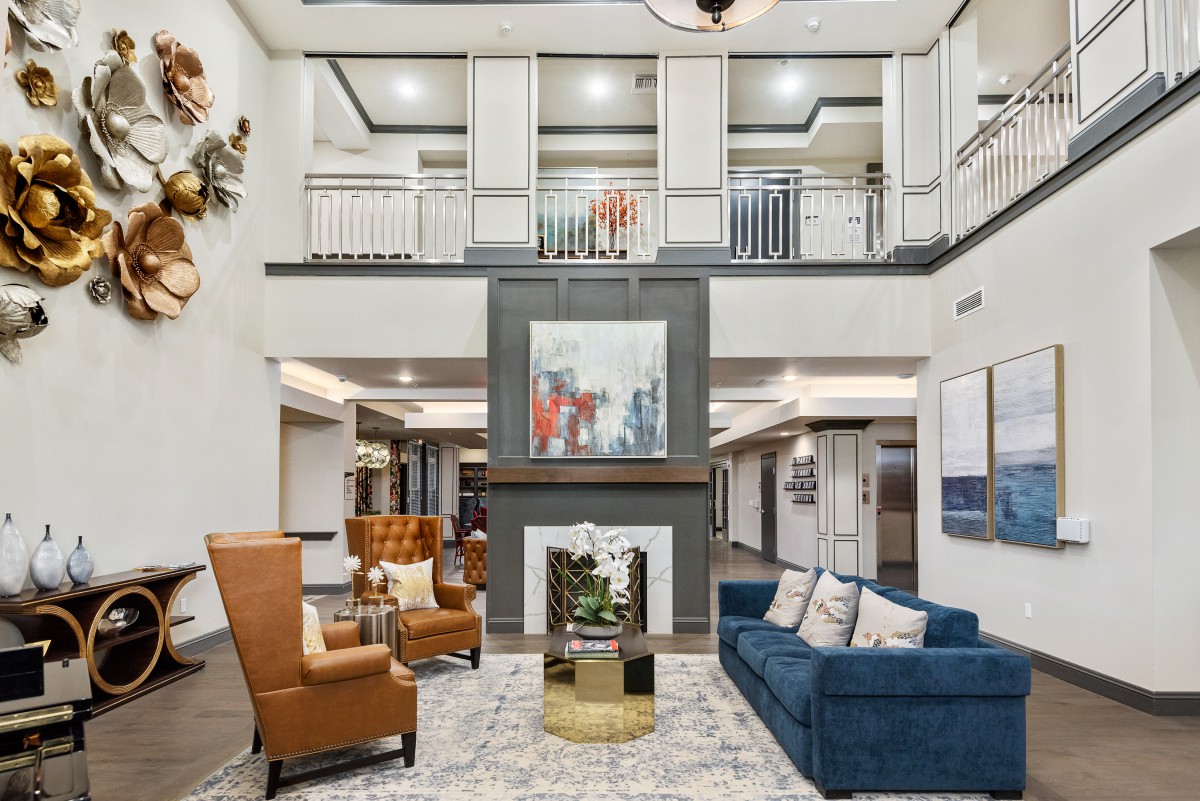 A modern lobby with comfortable seating, a central fireplace, and contemporary artwork.