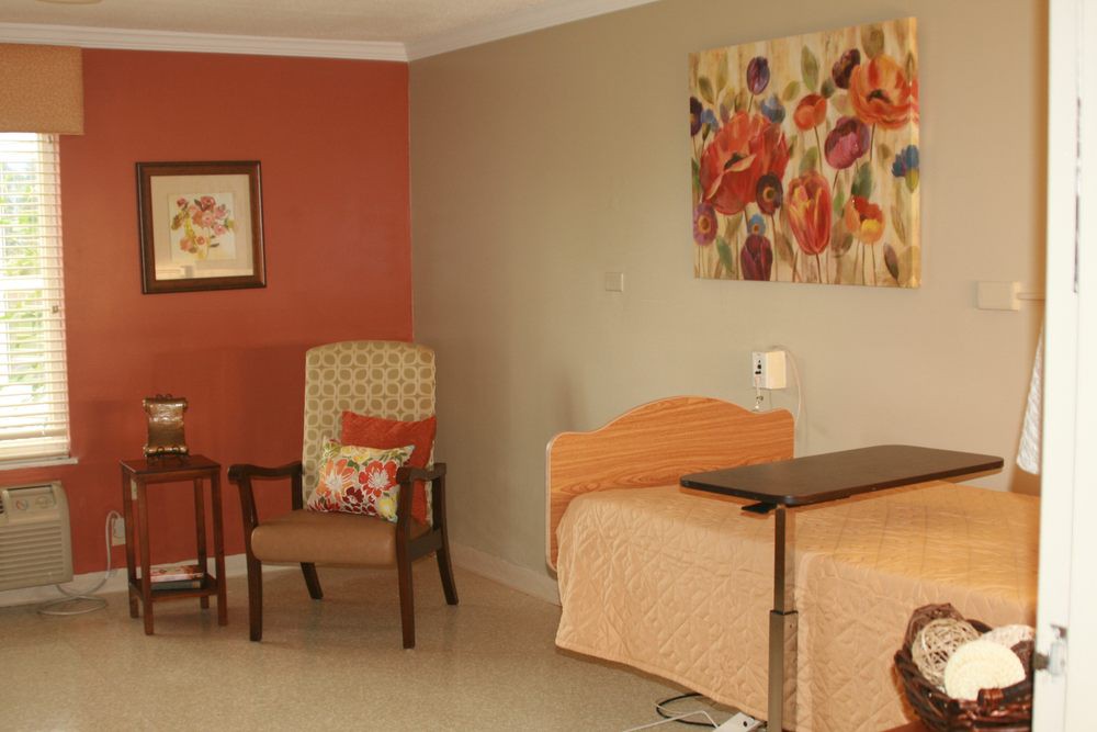 A cozy bedroom with a single bed, chairs, and vibrant artwork on the walls.