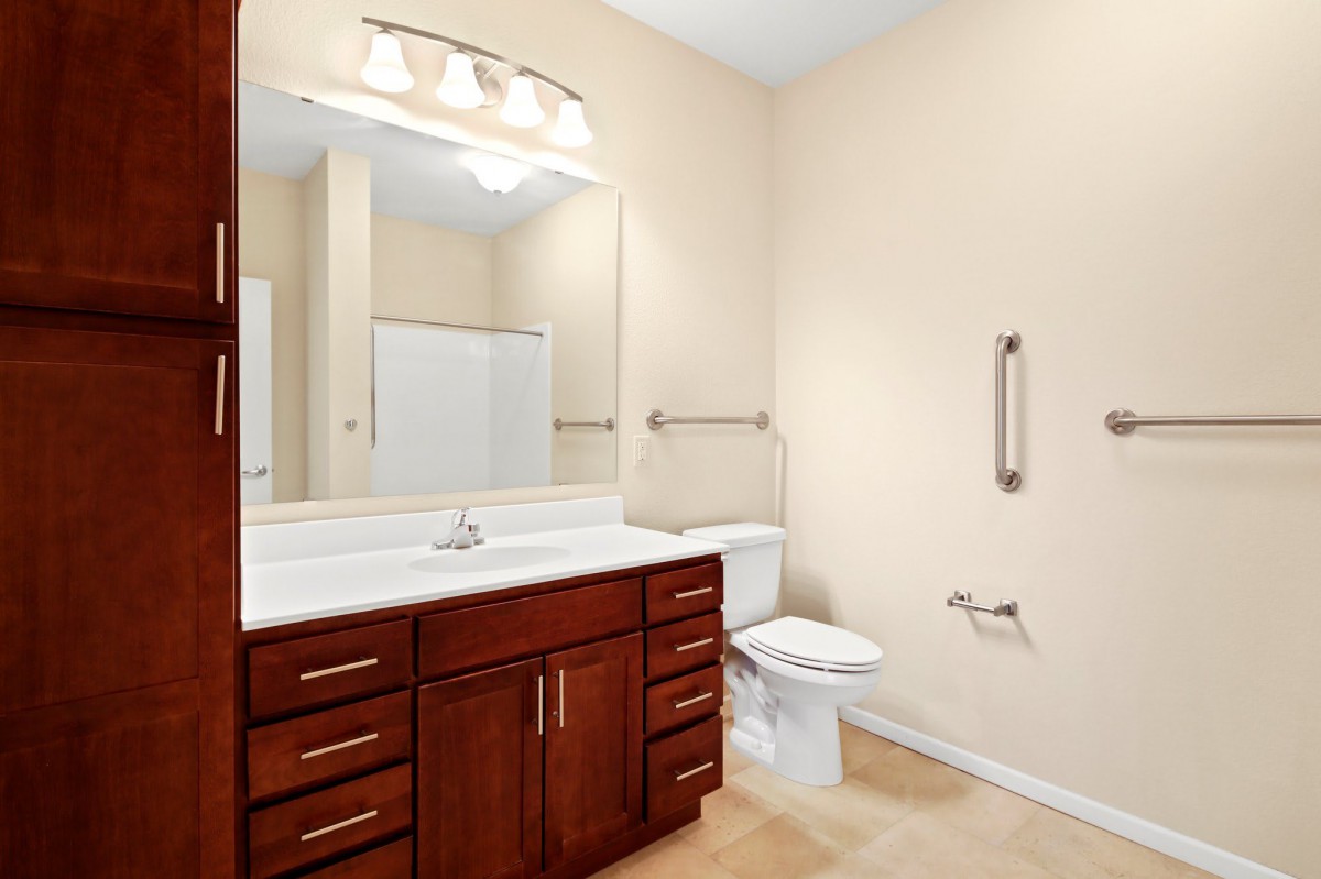 A modern bathroom with a wooden cabinet, large mirror, and a toilet.