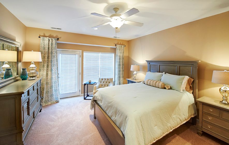 A cozy and well-lit bedroom with a large bed, ceiling fan, and elegant decor.