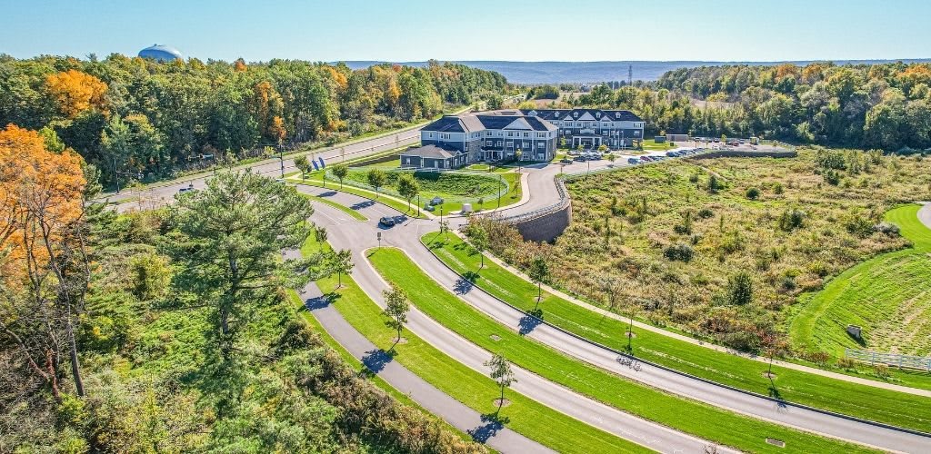 Aerial view of a landscaped area with roads and a large building surrounded by greenery.