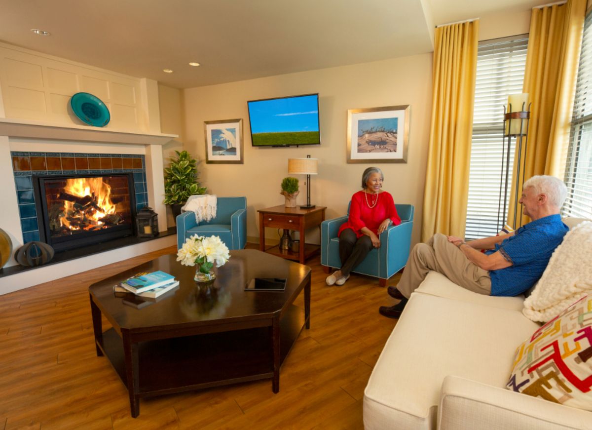 A cozy living room with a fireplace, television, and people seated comfortably.