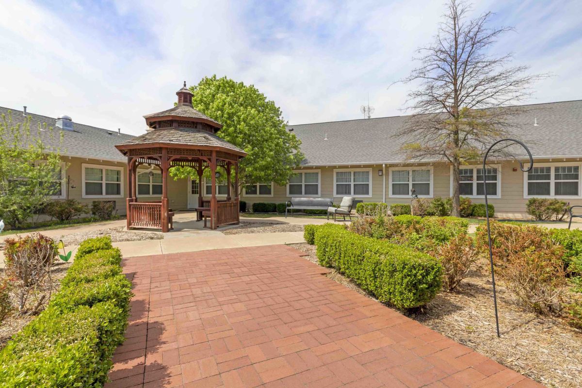 A peaceful courtyard featuring a wooden gazebo surrounded by well-maintained landscaping.