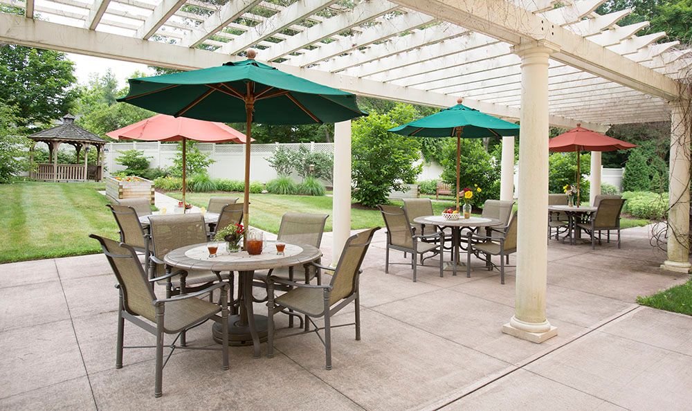 An inviting outdoor patio area with tables and umbrellas surrounded by lush greenery.