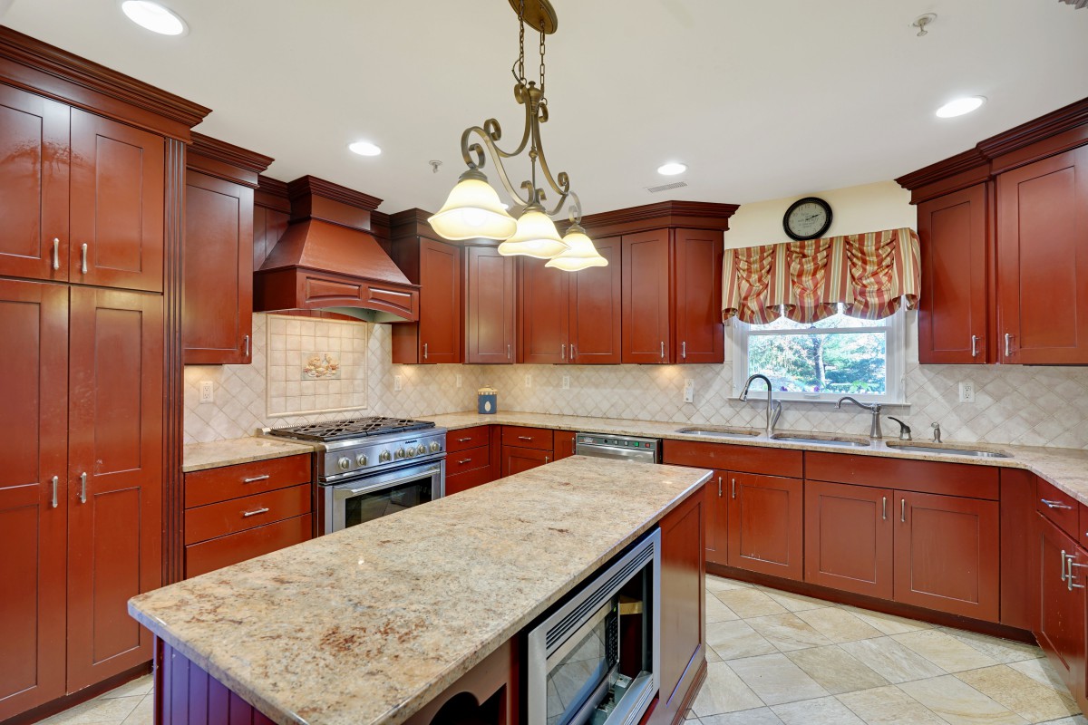 A spacious kitchen with wooden cabinets, a granite island, and modern appliances.