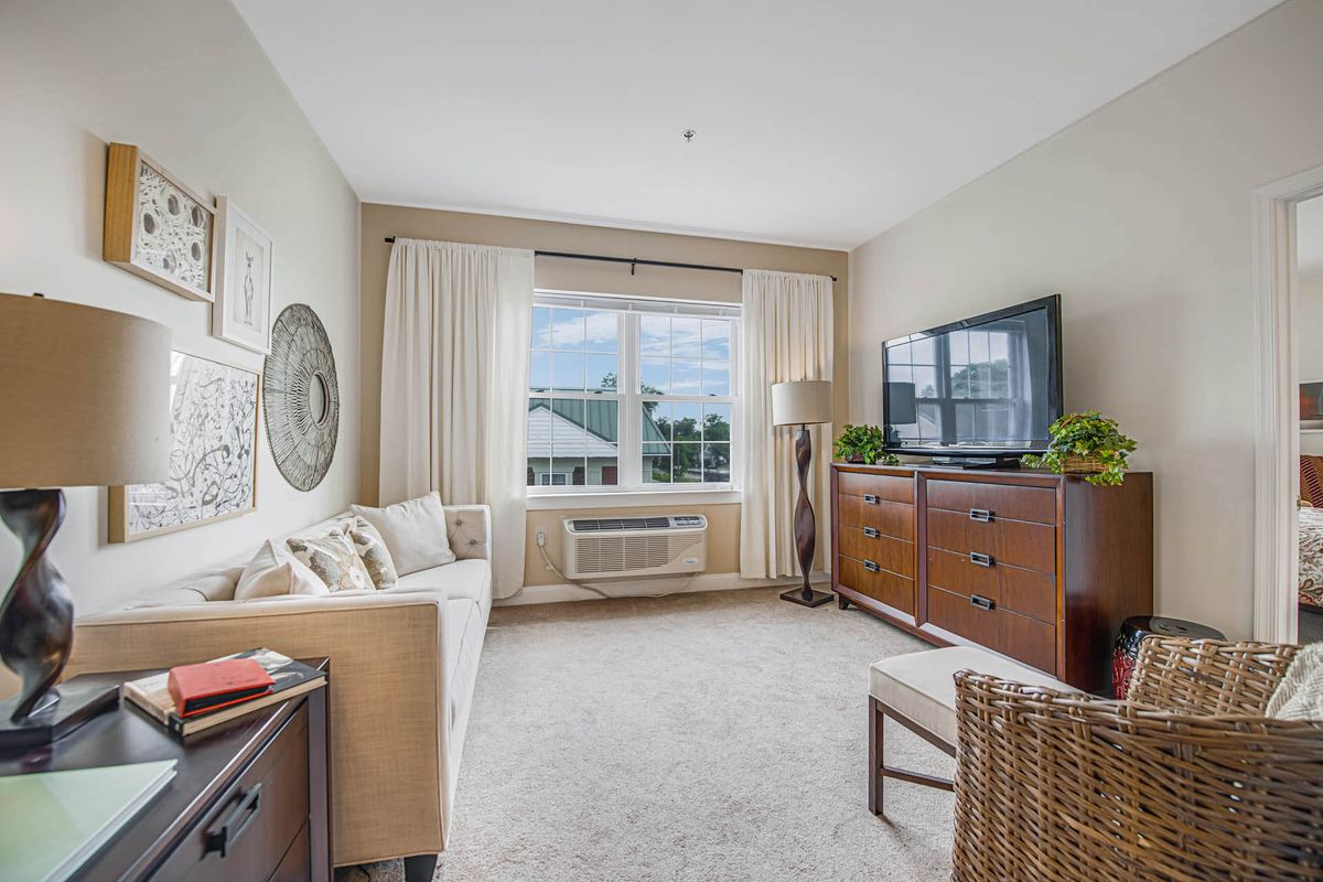 A cozy living room with a sofa, television, and large window with curtains.