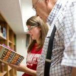 Two people browsing a book in a library.