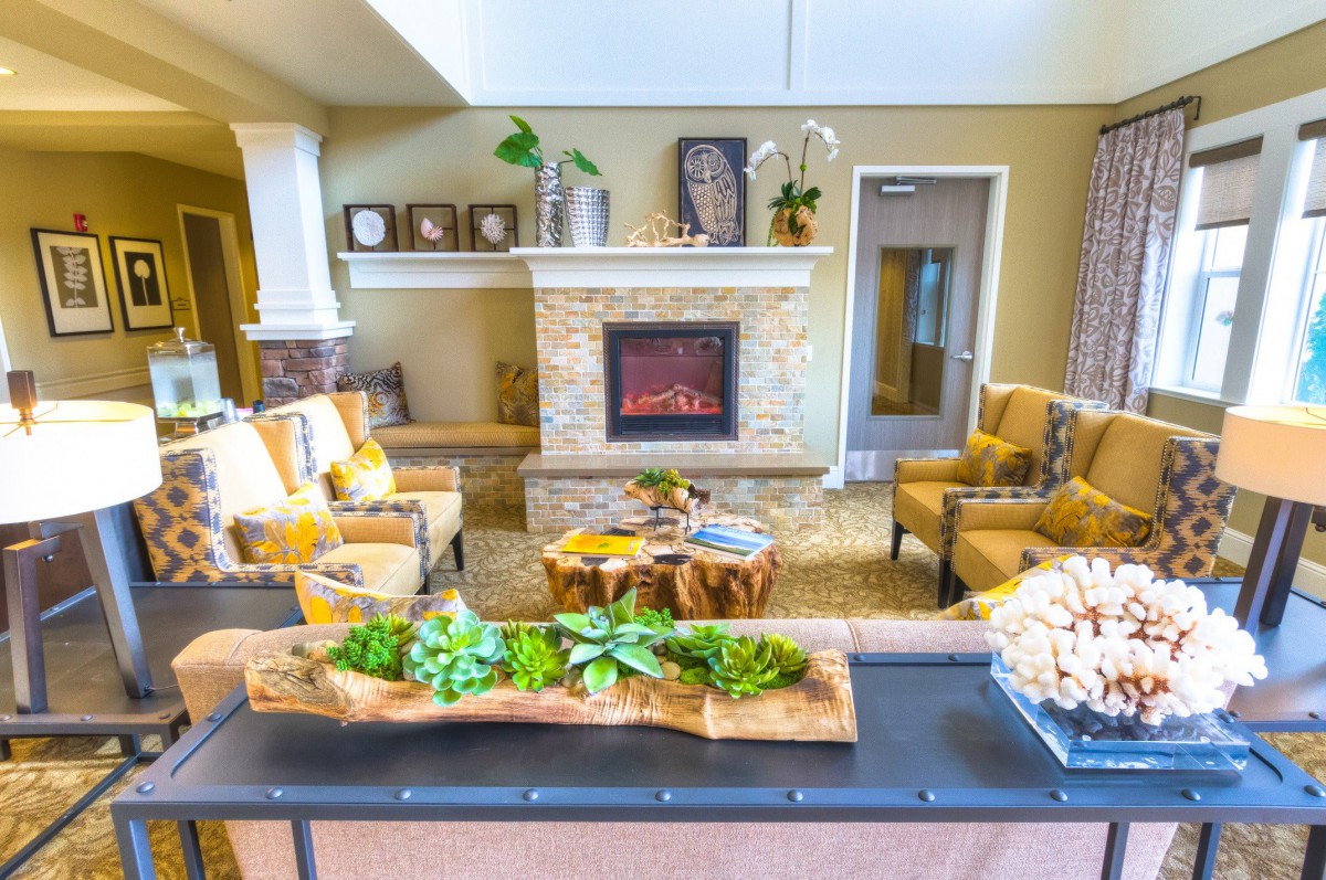 A cozy living room with a fireplace and comfortable seating arrangement, adorned with plants and stylish decor.