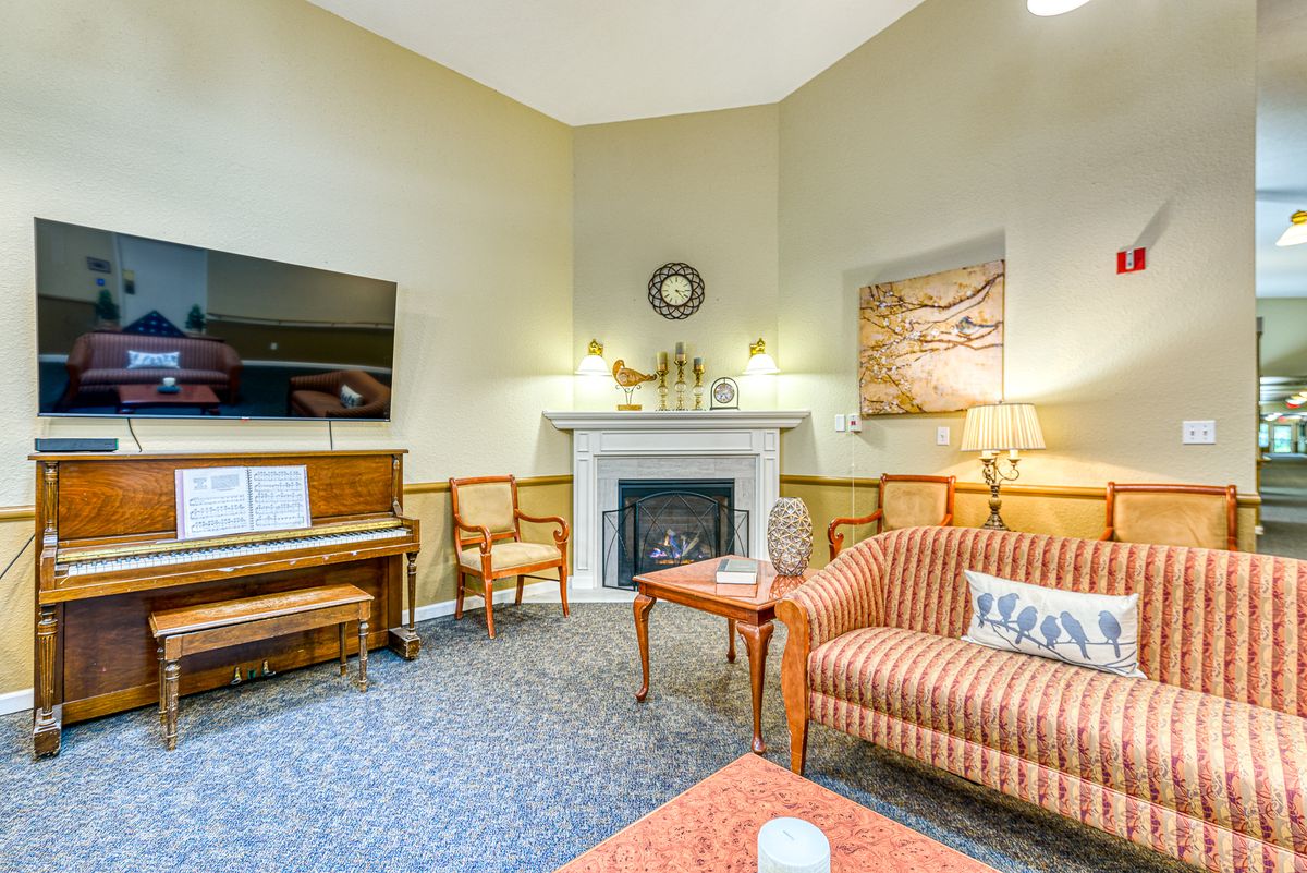 A cozy living room with a fireplace, piano, and comfortable seating area.