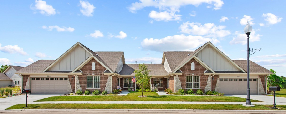 A suburban duplex with a well-maintained lawn under a clear blue sky.