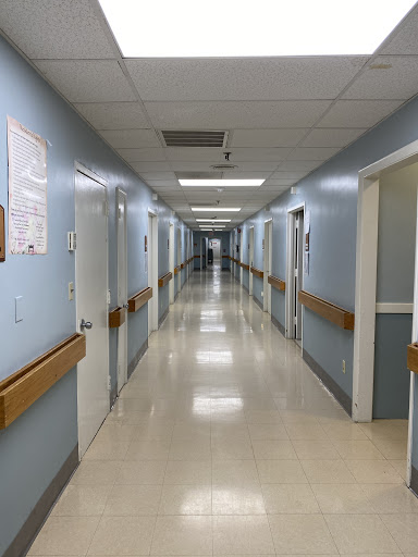 A long, clean corridor in a hospital, featuring blue walls and well-lit spaces.