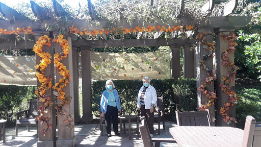 Two women enjoying a sunny day in a beautifully decorated garden area.
