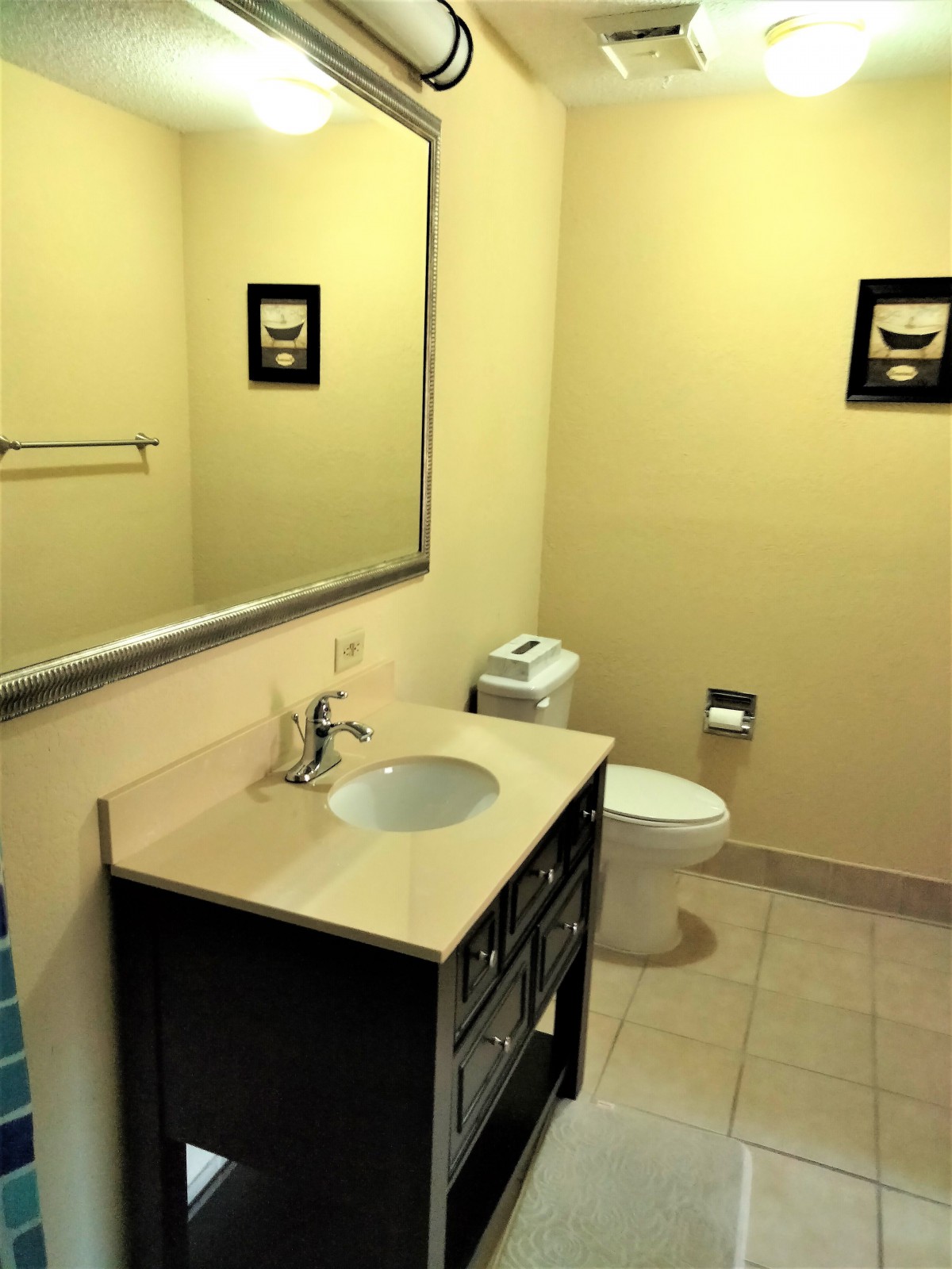 A clean and simple bathroom with a sink, mirror, and toilet.