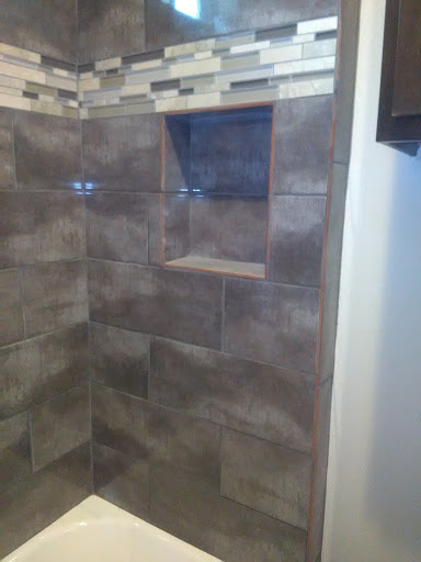 A modern shower featuring stylish tiled walls and a built-in shelf.