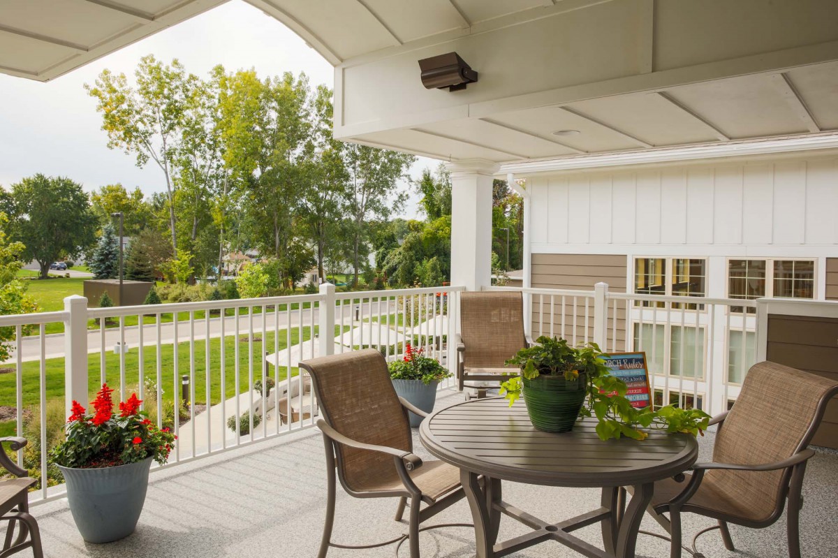 A cozy patio with outdoor furniture overlooking a lush garden.