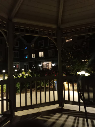 A serene nighttime view from a gazebo overlooking a well-lit garden.