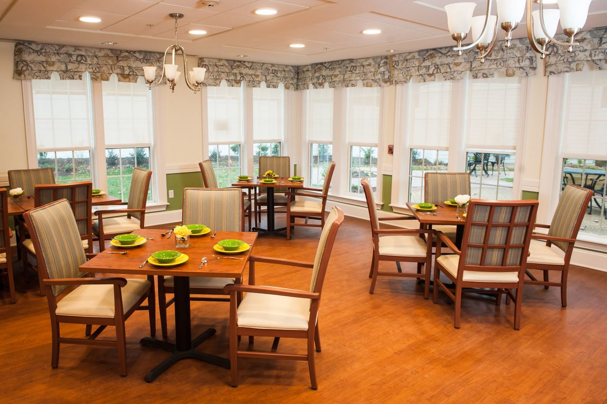 A well-lit dining room with elegant furniture and natural light streaming through large windows.
