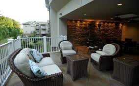 A cozy outdoor patio with rattan furniture and a stone accent wall.