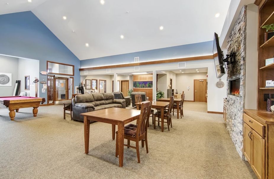A spacious lounge area with tables, chairs, a sofa, and a wall-mounted television.