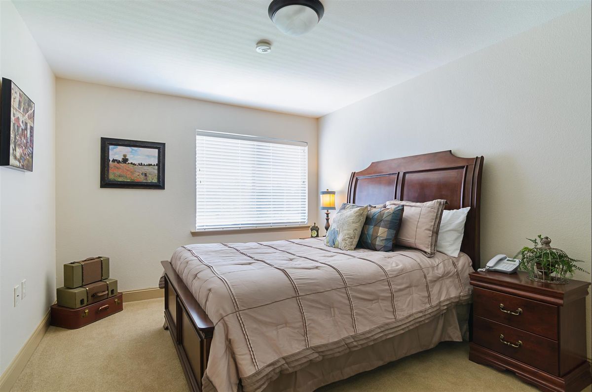 A cozy bedroom with a neatly made bed, bedside tables, and a window providing natural light.