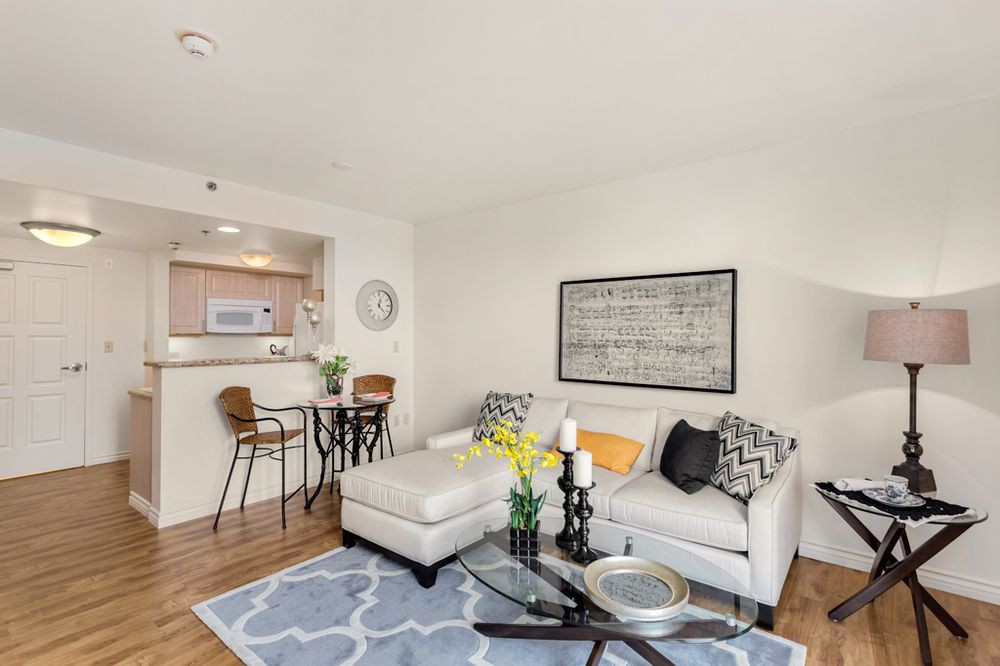 A cozy living room with a stylish sofa, coffee table, and a view into the kitchen.
