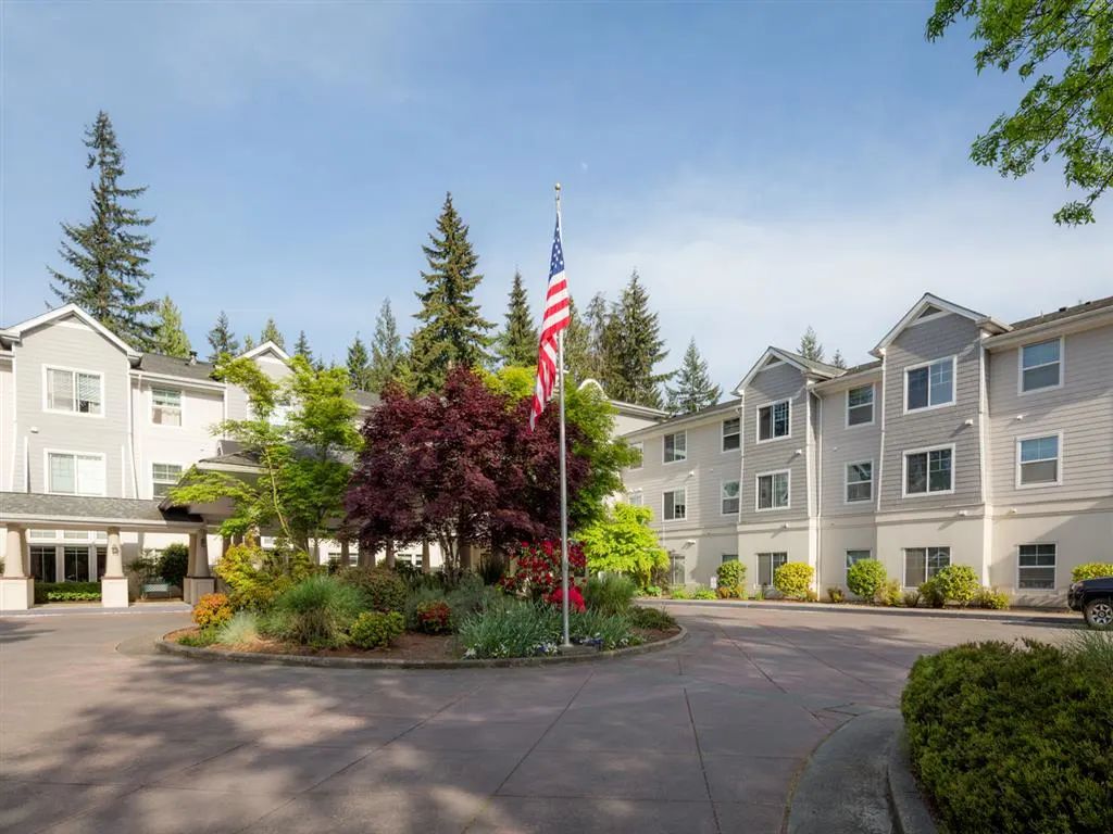 A residential building surrounded by trees with a flagpole in front.