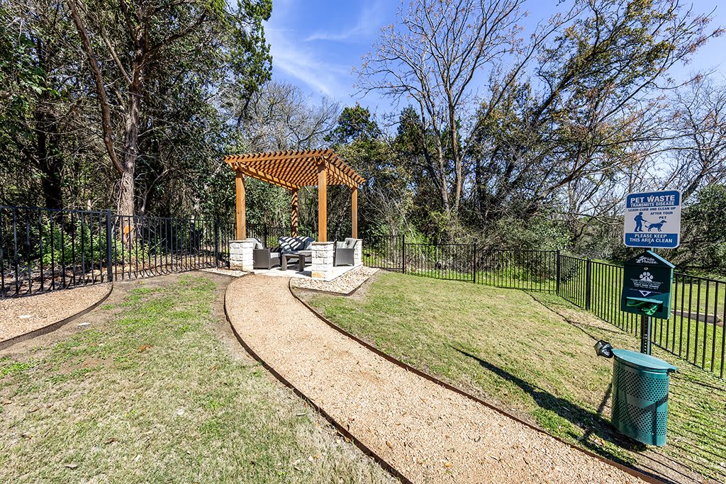 A serene garden with a pergola and a winding pathway surrounded by trees.