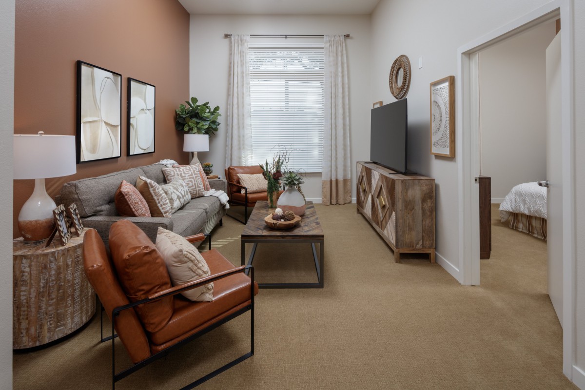 A modern living room featuring a comfortable sofa, armchairs, and a stylish TV stand with decorative elements.