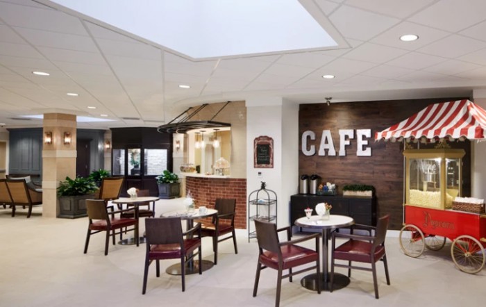 A modern cafe interior with tables and chairs, featuring a brick wall and stylish decor.