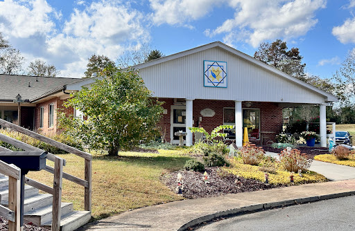 A welcoming building surrounded by a well-maintained garden under a partly cloudy sky.