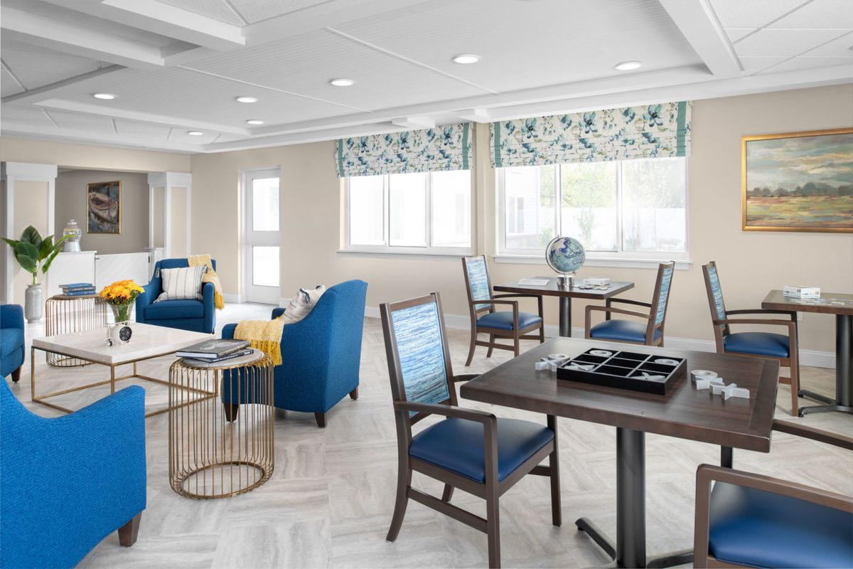 A modern and bright interior featuring blue chairs and tables, with large windows letting in natural light.