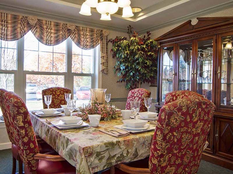 A cozy dining room with an elegantly set table and floral-patterned chairs.