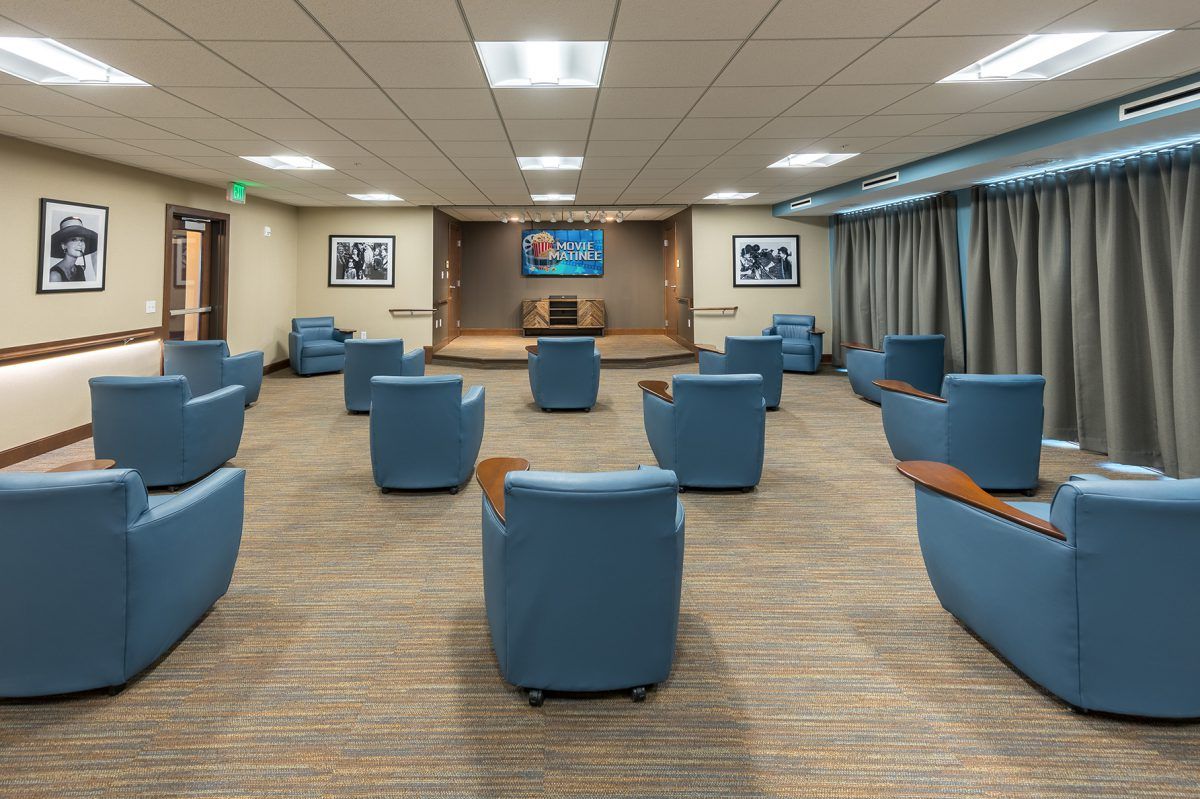 A modern conference room with blue chairs arranged facing a stage.
