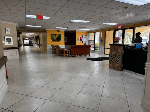 A spacious lobby area featuring comfortable seating and a reception desk, illuminated by natural light.