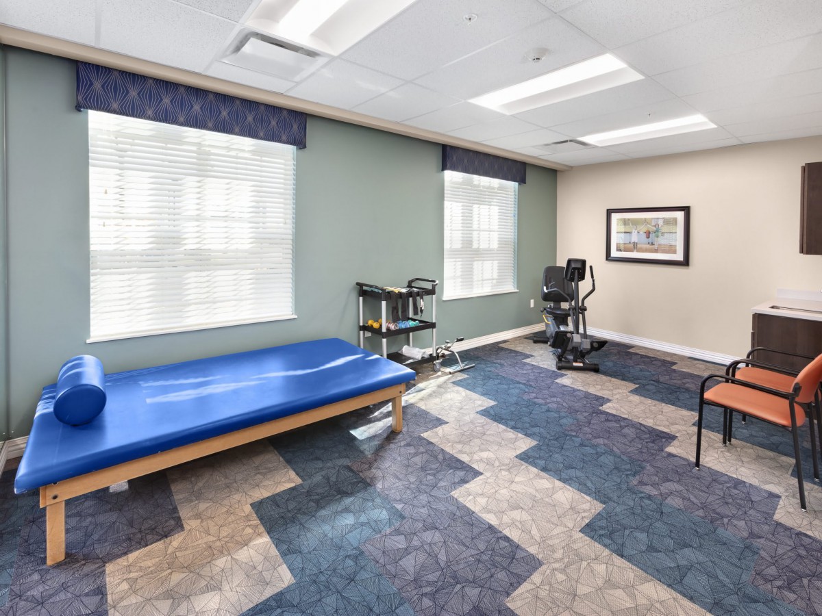 A rehabilitation room equipped with a therapy bed and exercise equipment.