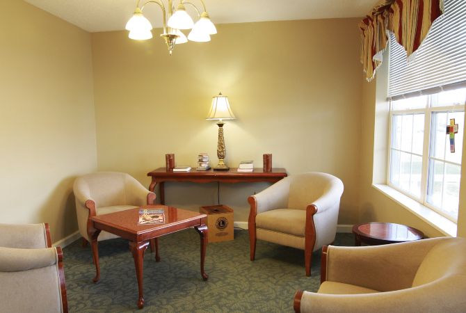 A cozy living room with comfortable chairs, a wooden table, and a lamp creating a warm atmosphere.