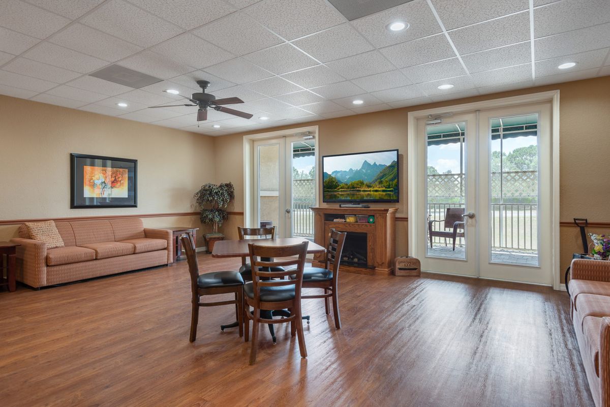 A cozy living room with a fireplace, TV, and comfortable seating area opens to a balcony.