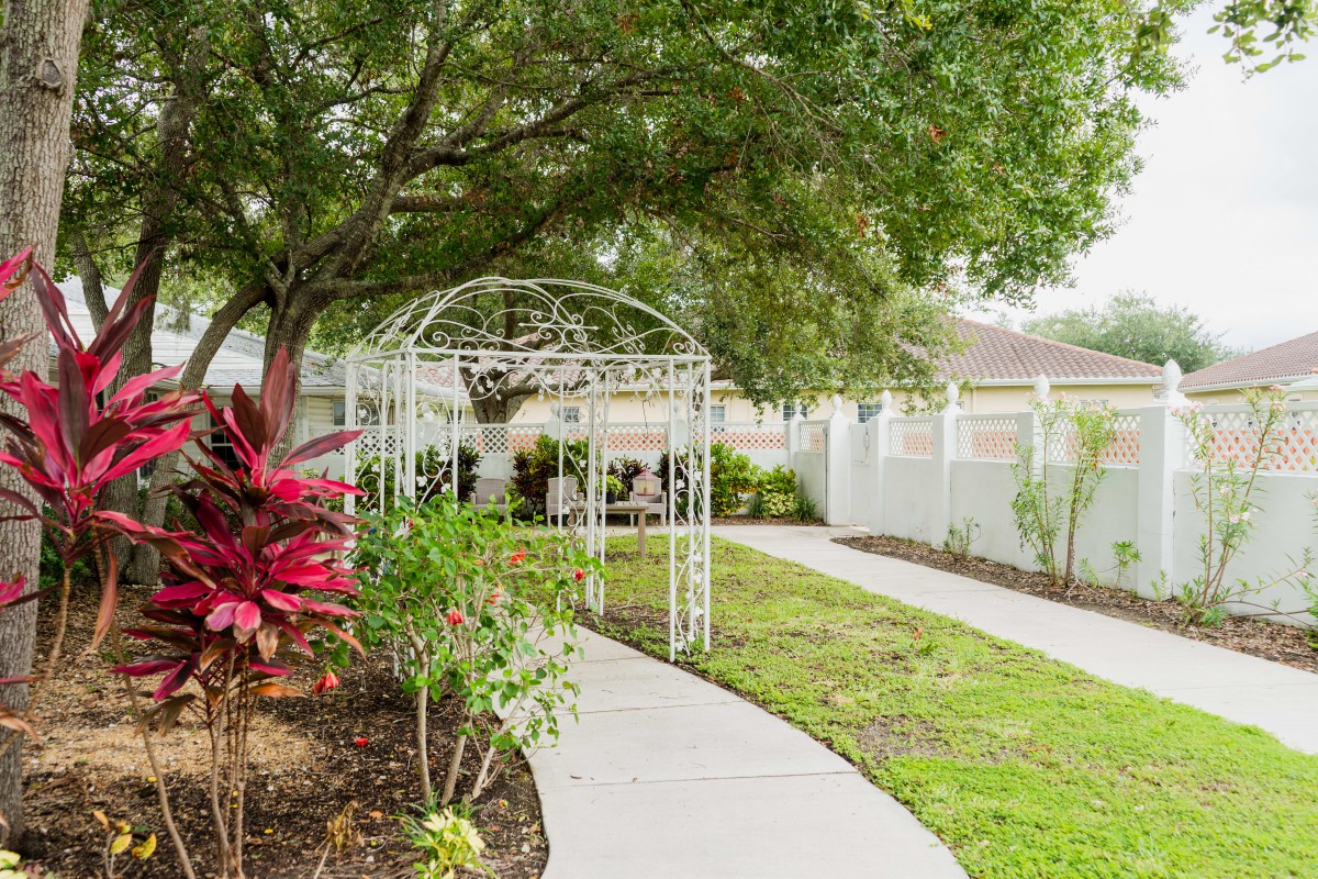 A peaceful garden pathway leading to a gazebo, surrounded by lush greenery.