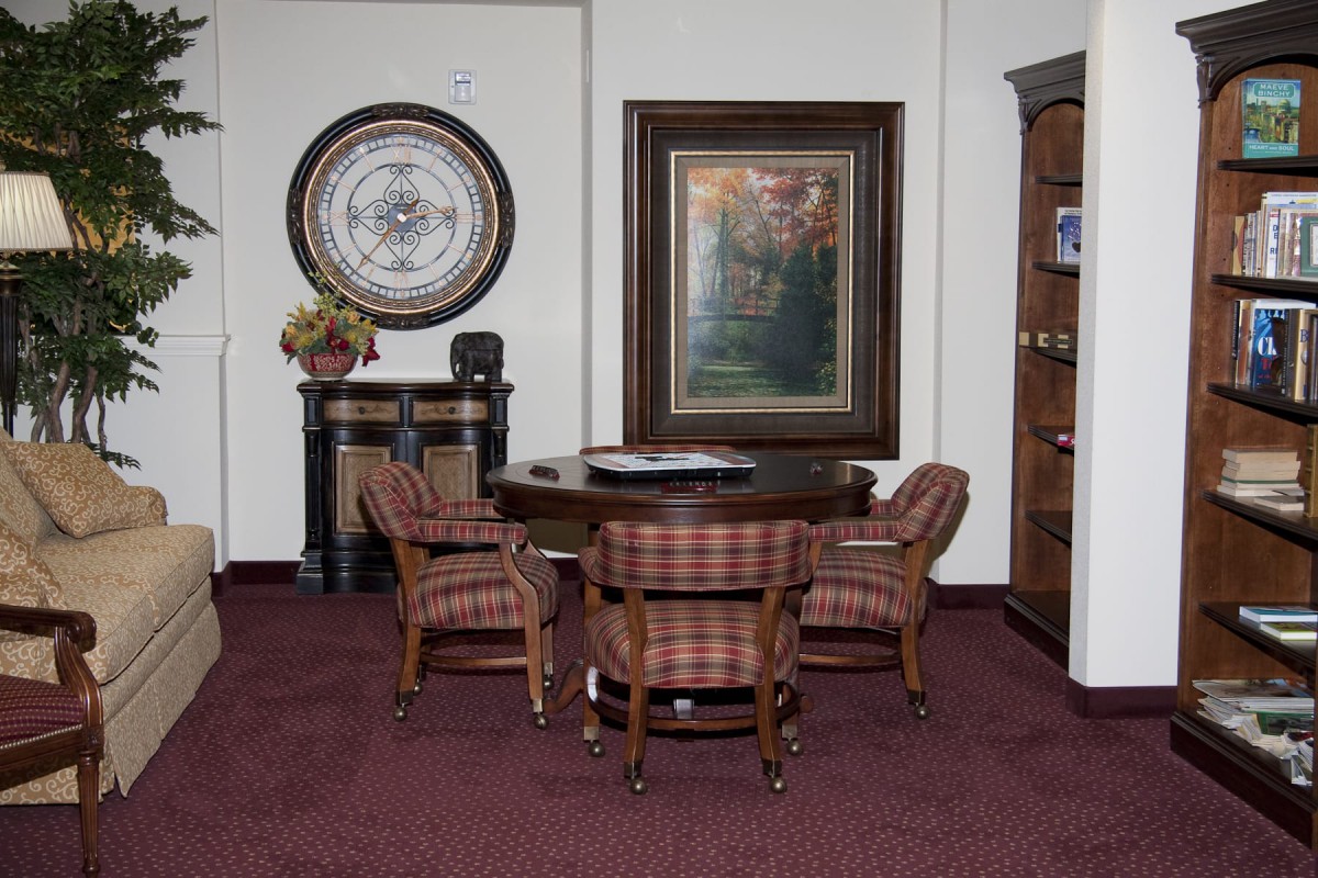 A small office area with a round table surrounded by four chairs, featuring wall art and decorative elements.