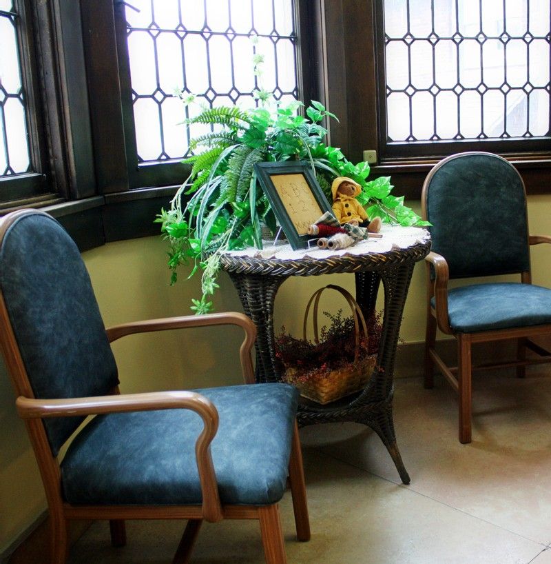 A cozy waiting area with two chairs and a decorated table featuring an indoor plant by the window.