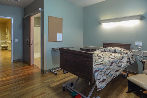 A hospital room featuring a bed and basic furnishings, designed for patient care.