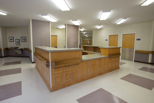 A spacious and well-lit reception area featuring a wooden counter and clean, modern design.