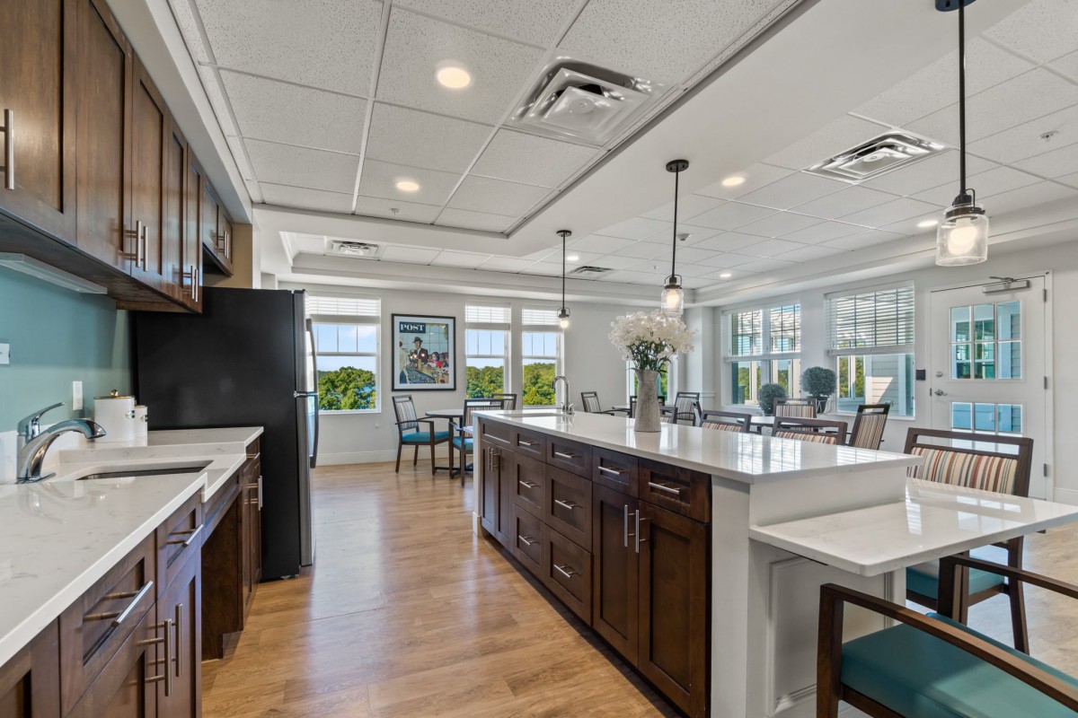A modern kitchen and dining area featuring a spacious island counter and sleek pendant lighting, with large windows allowing natural light to fill the open space.