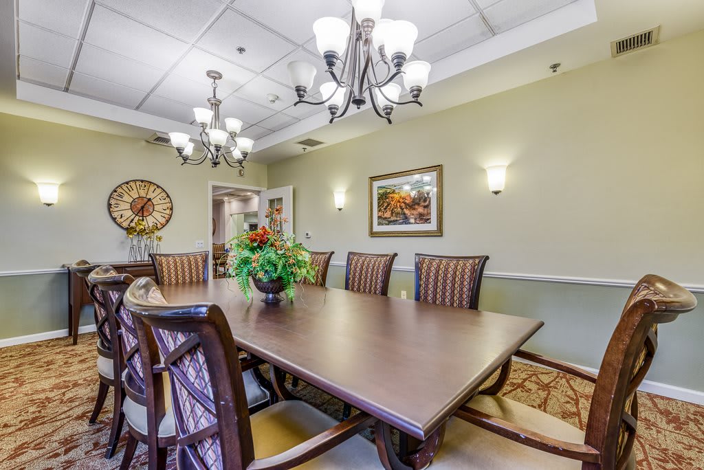 A well-decorated dining or conference room with a large table, elegant chairs, and chandeliers.