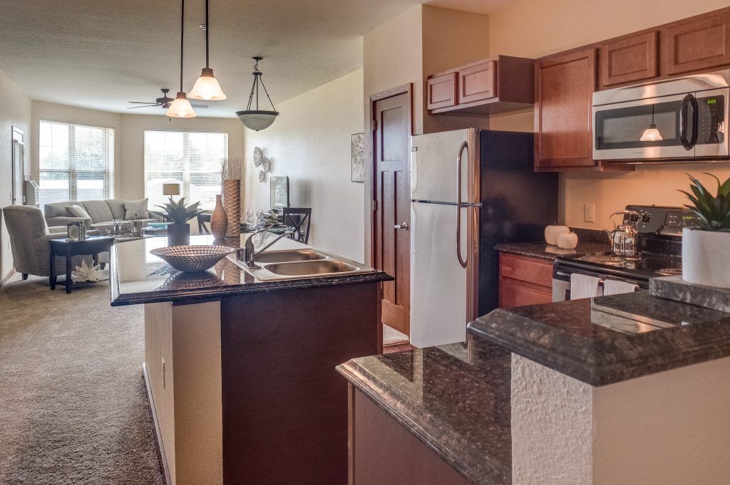 A modern kitchen in an apartment with wooden cabinets, granite countertops, and stainless steel appliances.