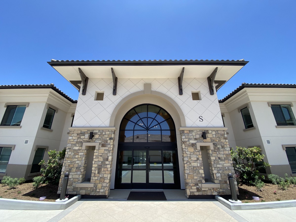 A modern building facade featuring a large arched window and stone accents.