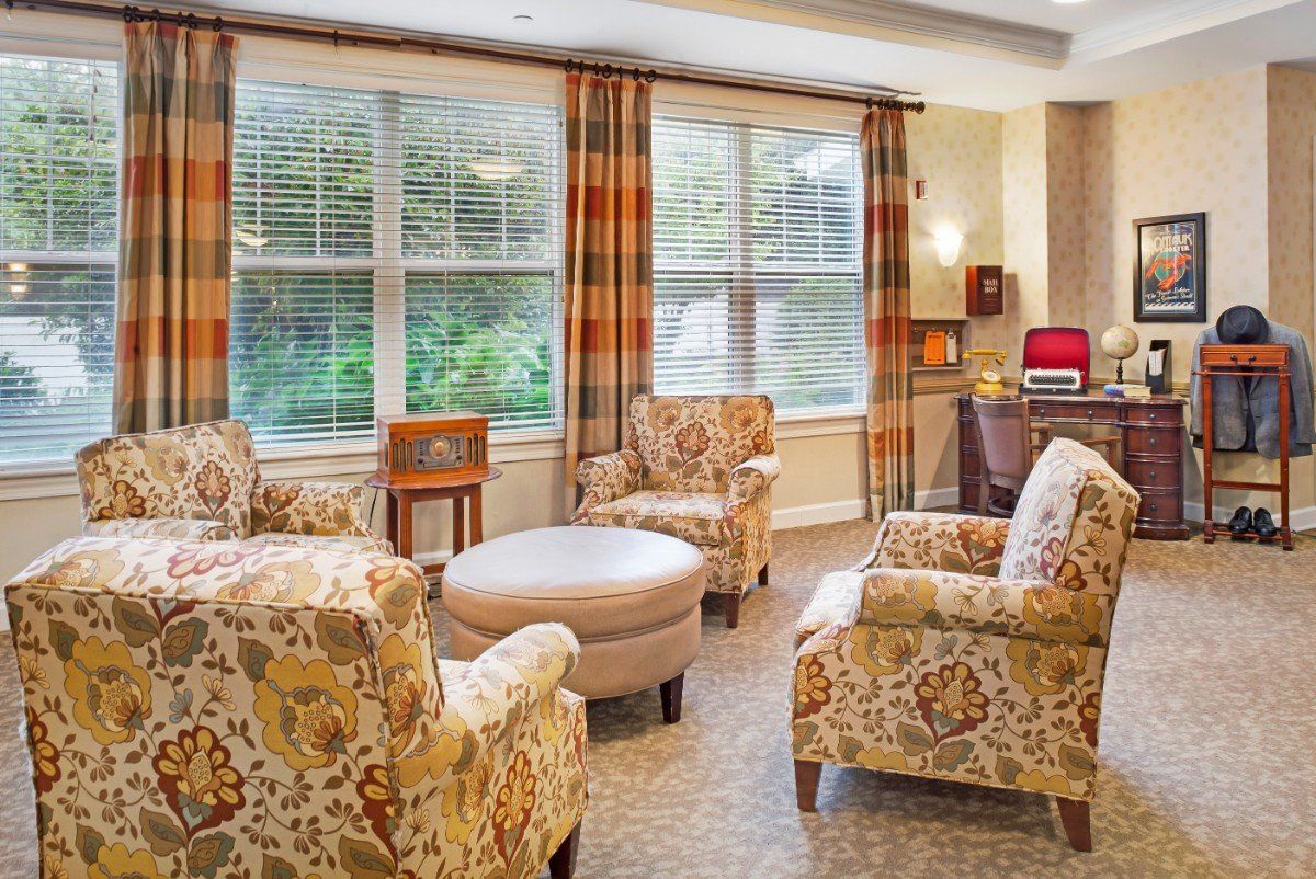 A cozy living room with patterned armchairs and large windows.